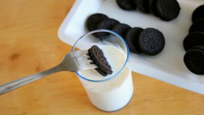 oreo dunk with fork into a glass of milk