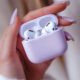 Apple AirPods Pro 2 - A hand with manicured nails holds an open lavender case containing Apple's AirPods Pro 2, showcasing their sleek white design.