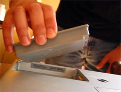 A Hand Is Inserting A Rectangular Battery Into An Electronic Device, Reminiscent Of Ensuring Laptops And Iphones Have Fresh Power Sources To Maximize Battery Life.