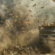 Bees Hunt Landmines In Ukraine - A large swarm of bees surrounds a rusted metal drum placed in a grassy, dust-filled area, buzzing like distant drones.