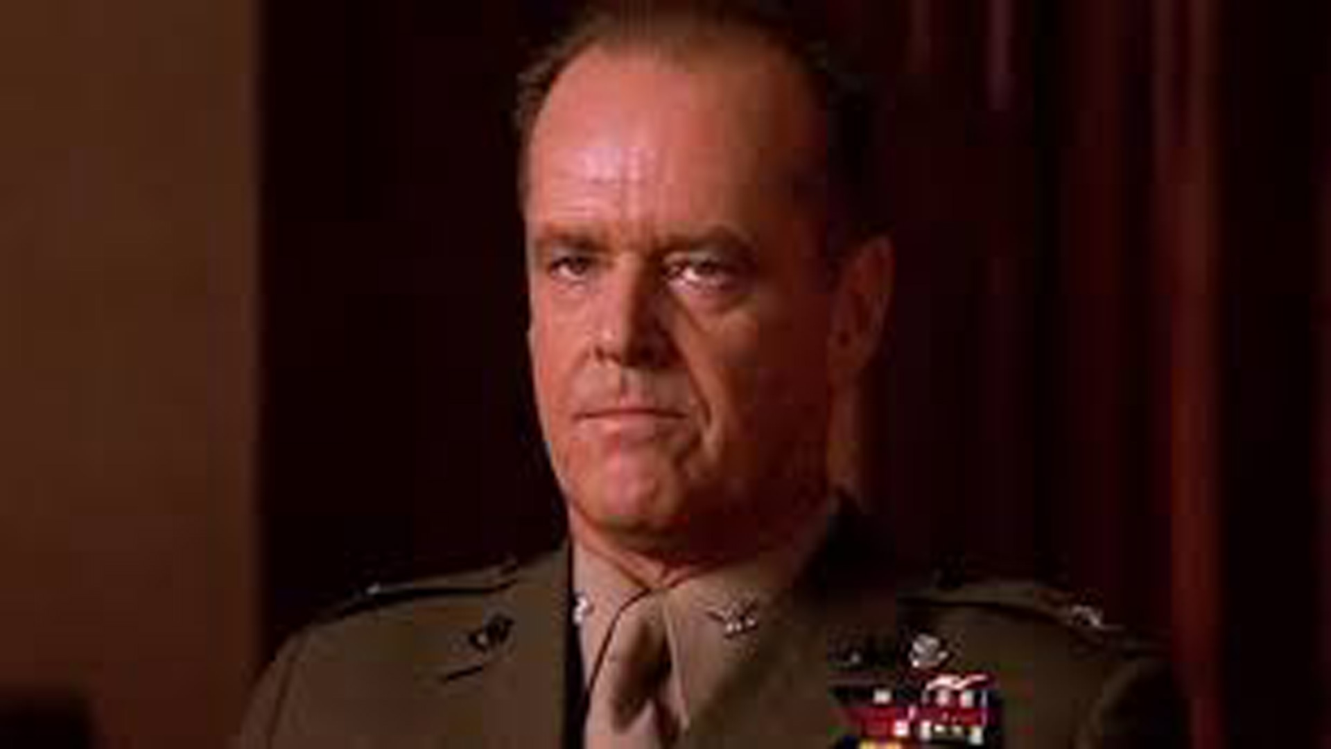 A Stern-Looking Man In A Military Uniform Adorned With Various Medals, Seated Against A Dark Background, Exuding An Aura Reminiscent Of A Few Good Men.