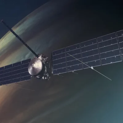 Europa Clipper - A Satellite With Large Solar Panels Orbits A Planet With Swirling Cloud Patterns, Advancing The Mission Of Space Exploration.