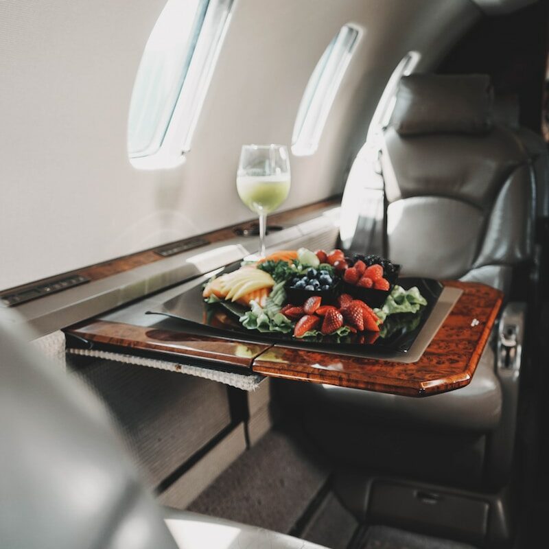First Class Seats On An Airplane - A Table With Food And Glasses On It