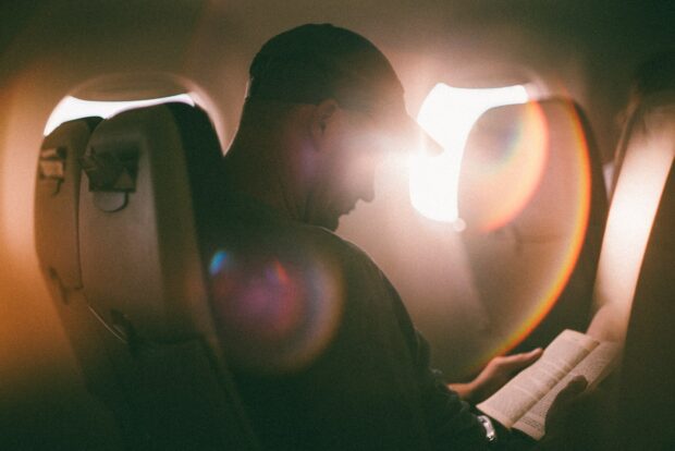 Man Sitting And Reading Book On An Airplane
