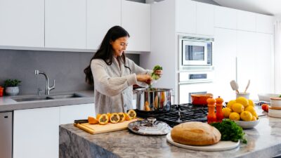 woman smiling while cooking healthy foods
