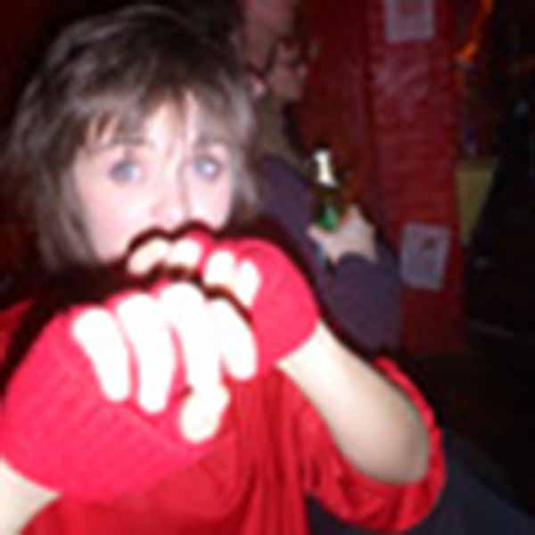 Helen Lawrence - A Woman In A Red Shirt Holding A Pair Of Gloves.