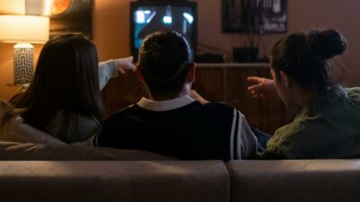 A group of people sitting on a couch watching tv.