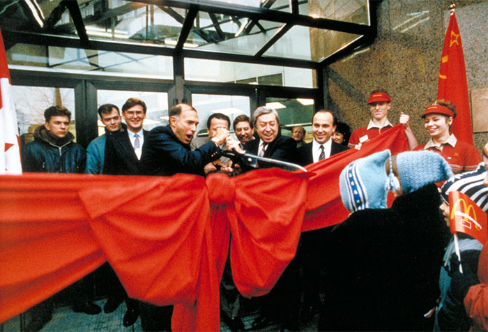 A Group Of People, Including A Representative From Russia'S First Mcdonald'S, Cutting A Red Ribbon For The Restaurant'S Grand Opening.