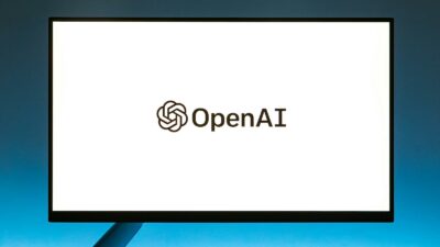 Minimalistic display of OpenAI logo on a monitor with a gradient blue background, representing modern technology.