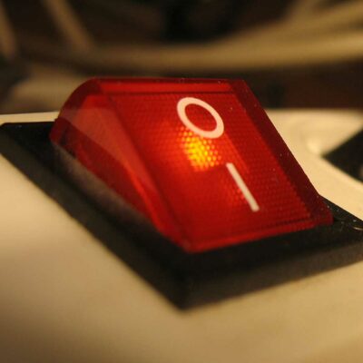 Close-Up Of A Red Rocker Switch On A White Surface, Offering A Guide To Decoding The 'I' (On) And 'O' (Off) Power Button Symbols.