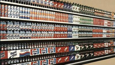A row of old soda cans on a shelf in a retro store.