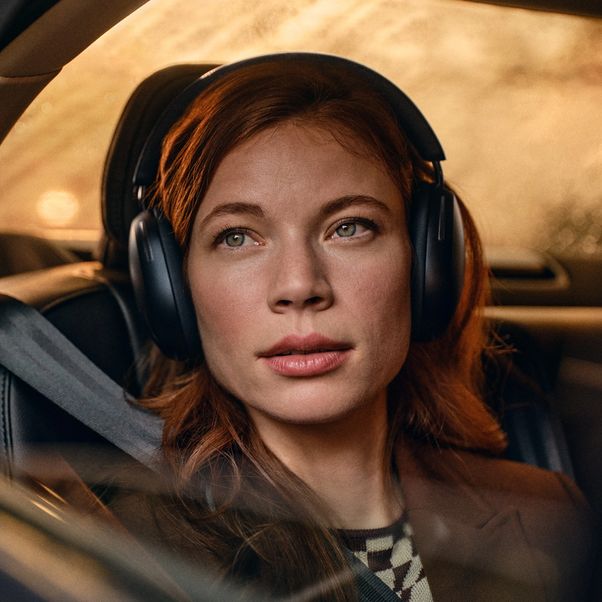 Sonos Ace Headphones - A Woman With Red Hair Wearing New Sonos Ace Headphones Sits In A Car Seat, Looking Out The Window.