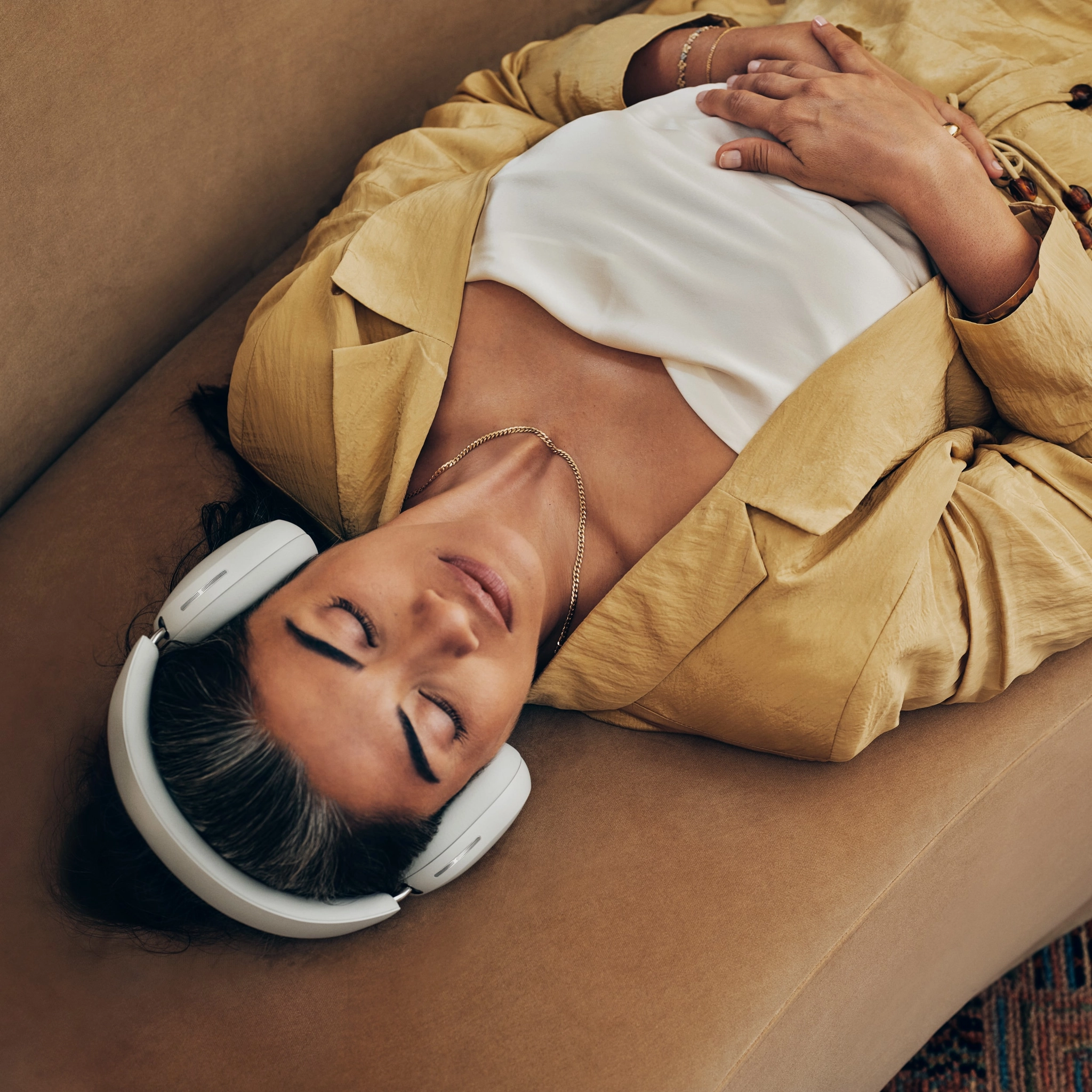 Sonos Ace Headphones: Redefining Immersive Audio On The Go - A Person In A Yellow Jacket And White Shirt Is Lying On A Couch With Eyes Closed, Wearing The New Sonos Ace Headphones And Resting Hands On Their Stomach.