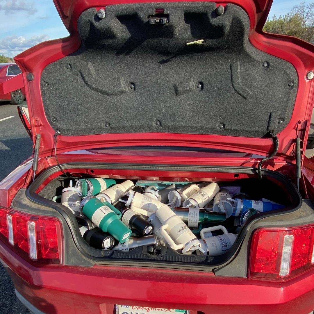 The Trunk Of A Red Ford Mustang Filled With Stanley Quenchers Water Bottles.