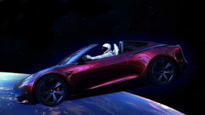 A red convertible car with a space-suited mannequin in the driver's seat floats in space above Earth.