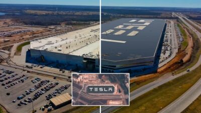 An aerial view of a Tesla factory featuring corporate branding through giant letters that spell TESLA.