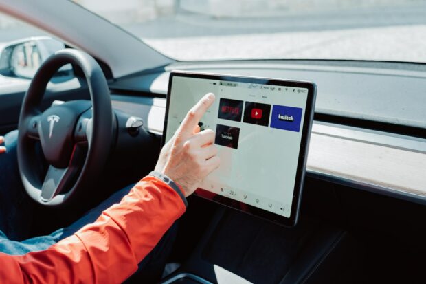 Driver Using A Car Touch Screen Inside A Tesla Model 3.