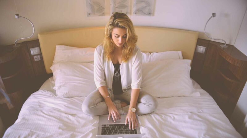 Woman Working On Laptop In Bed