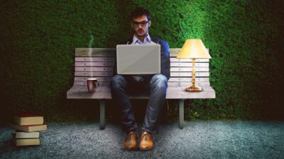 Man using a laptop on a park bench at night